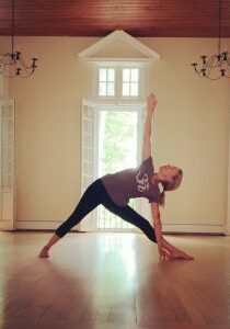 A woman practicing yoga in a bright, spacious room.